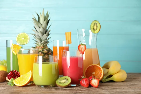 Artículos de vidrio con diferentes jugos y frutas frescas en la mesa — Foto de Stock