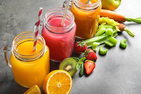 Mason jars with different juices and fresh ingredients on table — Stock Photo, Image