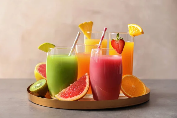 Tray dengan gelas jus yang berbeda dan buah segar di atas meja — Stok Foto