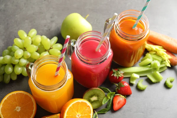 Mason jars with different juices and fresh ingredients on table — Stock Photo, Image