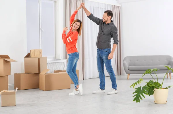 Pareja feliz bailando cerca de cajas móviles en su nueva casa —  Fotos de Stock