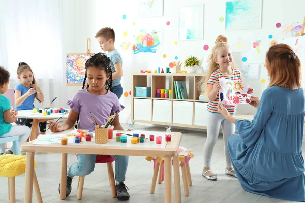 Crianças com professor feminino na aula de pintura em ambientes fechados — Fotografia de Stock