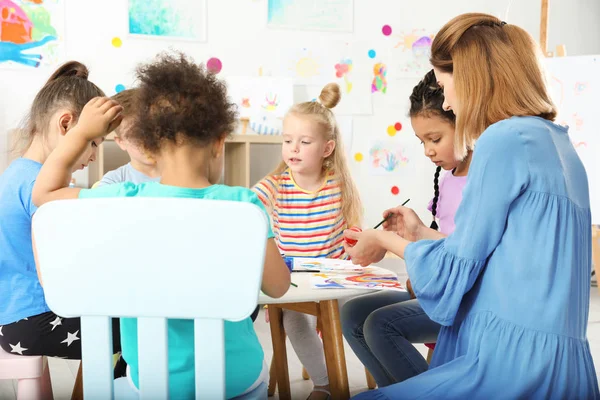 Crianças com professor feminino na aula de pintura em ambientes fechados — Fotografia de Stock