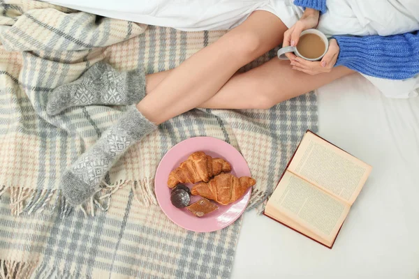 ベッドで朝食と本を持つ美しい若い女性、トップビュー。冬の雰囲気 — ストック写真