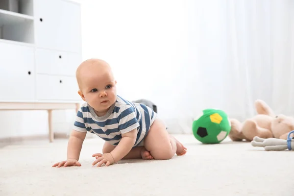 Bebé bonito rastejando no tapete dentro de casa — Fotografia de Stock