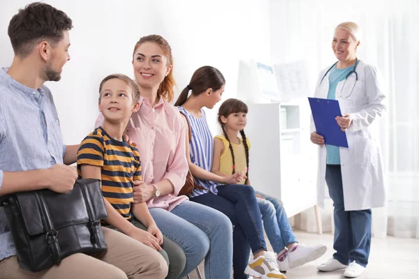 Parents with children waiting their turn in hospital. Visiting doctor