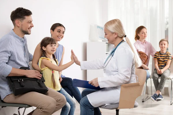 귀여운 아이는 그녀의 부모와 함께 앉아 병원에서 의사에게 하이 파이브를 제공 — 스톡 사진