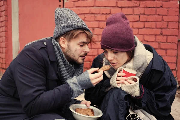 Pobre jovem casal com pão na rua suja — Fotografia de Stock