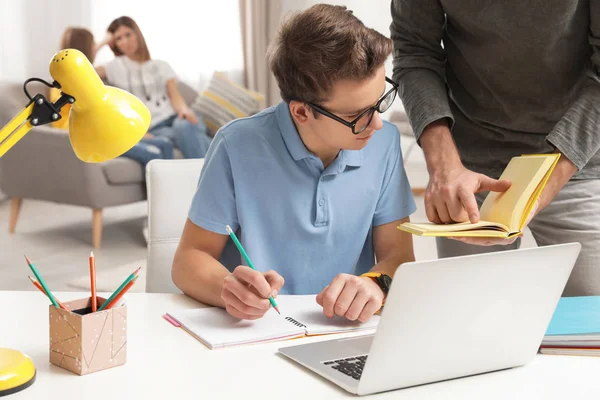 Père aidant son fils adolescent avec des devoirs à l'intérieur — Photo