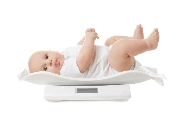 Cute little baby lying on scales against white background — Stock Photo, Image