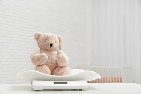 Escamas de bebé con oso de peluche en la mesa en la sala de luz. Espacio para texto —  Fotos de Stock