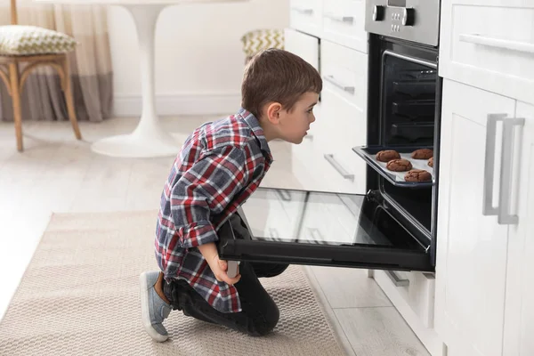 小男孩在厨房里用饼干打开烤箱 — 图库照片
