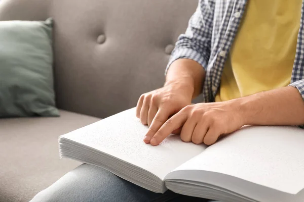 Hombre ciego leyendo libro escrito en Braille en sofá, primer plano — Foto de Stock