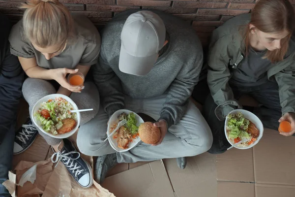 Pobres personas con platos de comida sentados en la pared en el interior, vista desde arriba — Foto de Stock