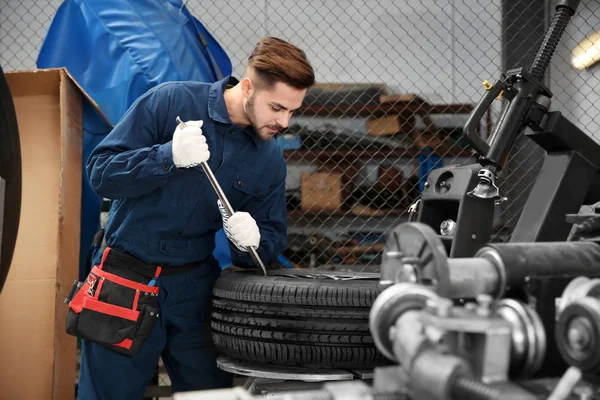 Técnico que trabalha com roda de carro na oficina de reparação automóvel — Fotografia de Stock