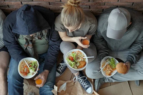 Pobres personas con platos de comida sentados en la pared en el interior, vista desde arriba — Foto de Stock