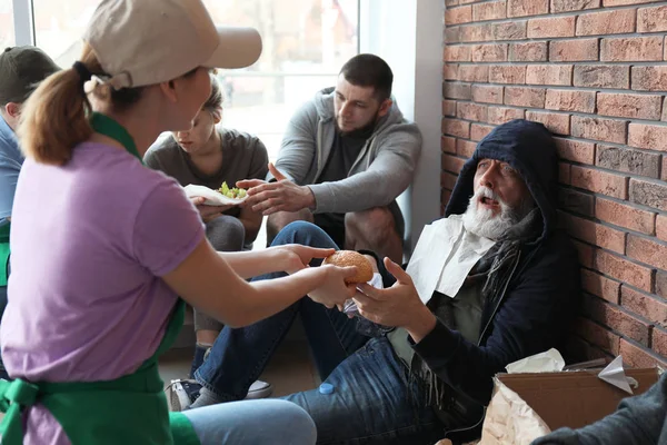 Gönüllü kapalı yoksul yaşlı adama yiyecek veren — Stok fotoğraf