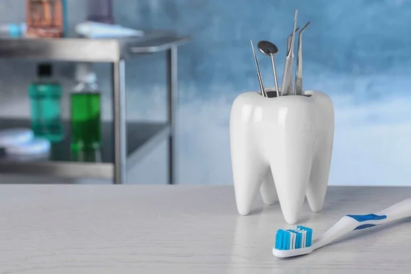 Toothbrush near holder with dentist tools on table. Space for text