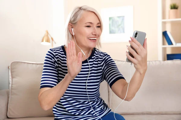 Зріла жінка використовує відео чат на мобільному телефоні вдома — стокове фото