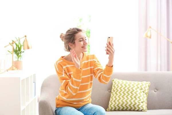 Mulher usando telefone celular para bate-papo por vídeo na sala de estar — Fotografia de Stock