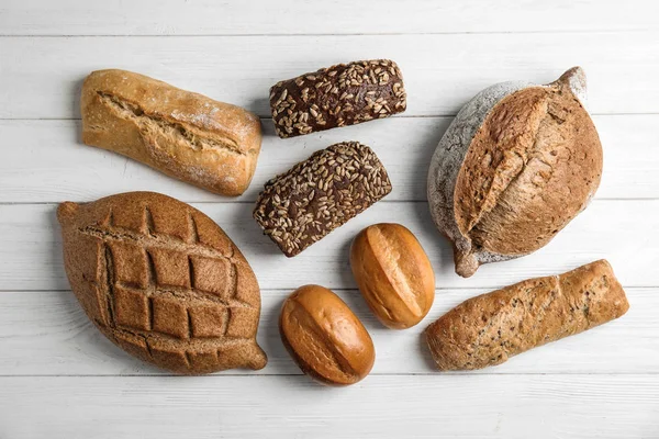 Tahta masanın üzerinde farklı taze ekmek türleri, düz yatıyordu.. — Stok fotoğraf
