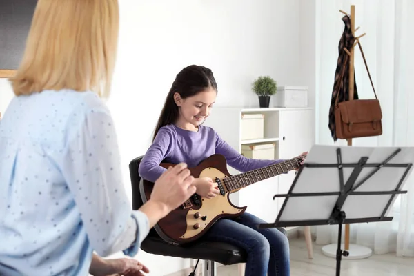 Niña tocando la guitarra con su profesor en la clase de música. Notas de aprendizaje — Foto de Stock