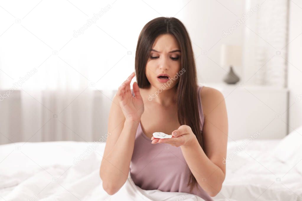 Beautiful woman holding cotton pad with fallen eyelashes indoors