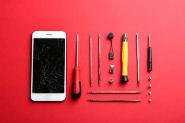 Renkli arka planda kırık cep telefonu ve onarım araçları ile düz döşeme kompozisyon