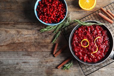 Ahşap arka plan üzerinde tavada kızılcık sosu ile Düz yatıyordu kompozisyon. Metin için alan