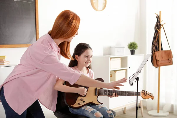 Dziewczynka gra na gitarze z nauczycielem na lekcji muzyki. Notatki edukacyjne — Zdjęcie stockowe