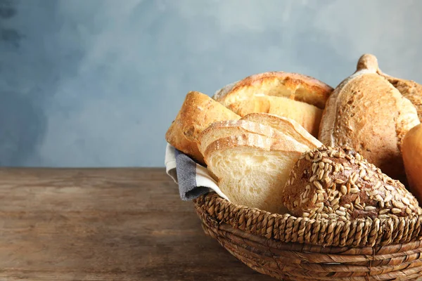 Cesto con pane fresco sul tavolo sullo sfondo di colore. Spazio per testo — Foto Stock