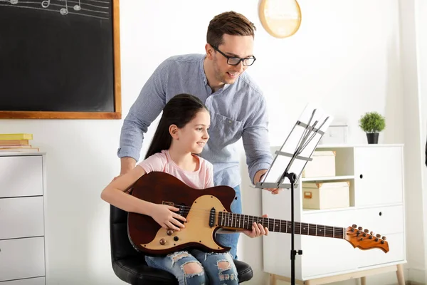 Klein meisje speelt gitaar met haar leraar op muziekles. Leer notities — Stockfoto