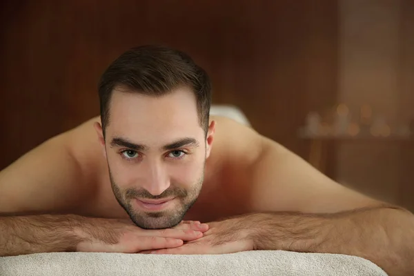 Красивий чоловік розслабляється на масажному столі в спа-салоні — стокове фото