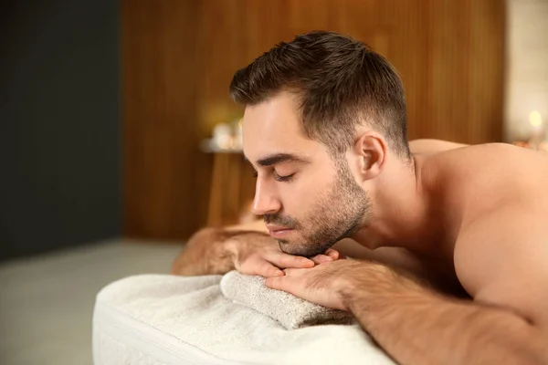 Schöner Mann entspannt sich auf Massagetisch im Wellness-Salon — Stockfoto