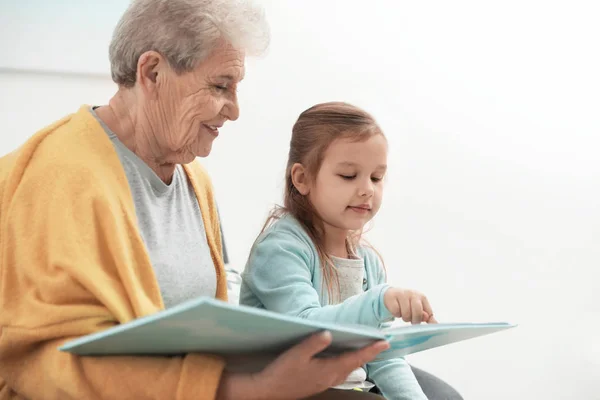 Fille mignonne et sa grand-mère lecture livre à la maison — Photo