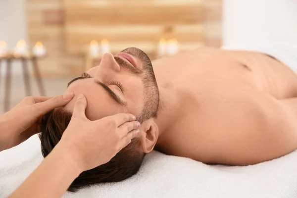 Handsome man receiving face massage in spa salon — Stock Photo, Image