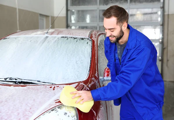 Worker cleaning automobile with sponge at professional car wash — Stock fotografie