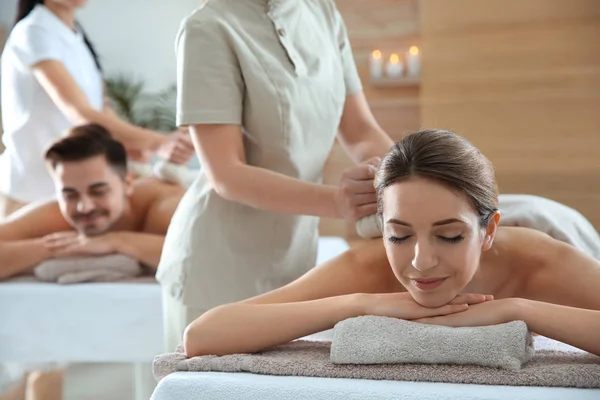 Romântico jovem casal desfrutando de massagem saco de ervas no salão de spa — Fotografia de Stock