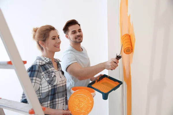 Happy couple painting wall indoors. Home repair — Stock Photo, Image