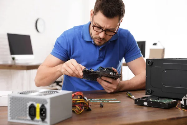 Técnico masculino que repara la computadora en la mesa en el interior —  Fotos de Stock