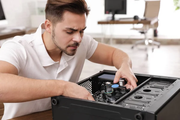 Чоловічий технік ремонтує комп'ютер за столом в приміщенні — стокове фото