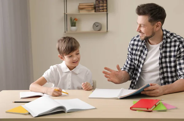 Papá ayudando a su hijo con la tarea escolar en casa — Foto de Stock
