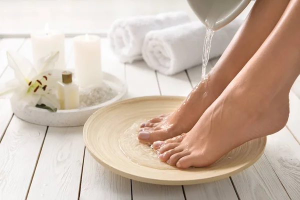 Вид крупным планом женщины, наполняющей посуду водой для ванны для ног в помещении. Лечение — стоковое фото