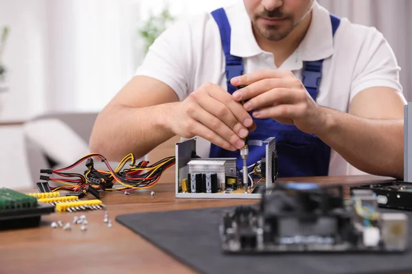 Técnico masculino que repara la unidad de la fuente de alimentación en la mesa en el interior, primer plano —  Fotos de Stock