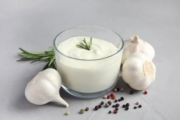 Verse knoflook bollen, kommetje saus, rozemarijn en peper op grijze achtergrond — Stockfoto