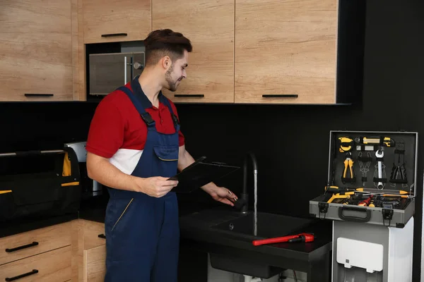 Mannelijke loodgieter in uniforme controle kraan in de keuken. Reparatie service — Stockfoto
