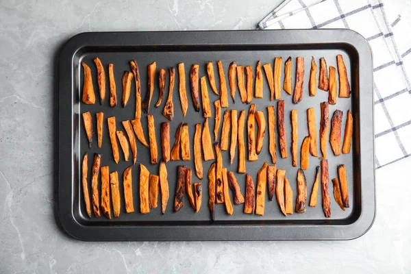 Bakplaat met zoete aardappelschijfjes op grijze achtergrond, bovenaanzicht — Stockfoto