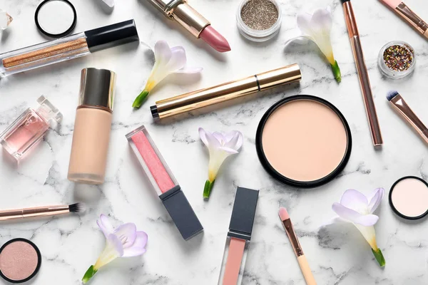 Många olika makeup produkter och vårblommor på marmor bakgrund, Flat Lay — Stockfoto