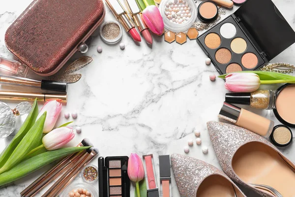 Veel verschillende make-up producten, schoenen en lente bloemen op marmeren achtergrond, platte lay. Ruimte voor tekst — Stockfoto