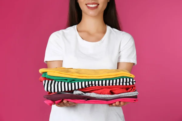 Молодая женщина держит чистое белье на цветном фоне, крупным планом — стоковое фото